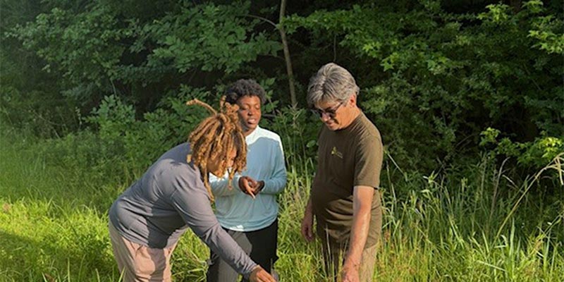 David Harper and Summer Interns Lucinda Duah and Madisyn Nooks review plant height in the prairie.